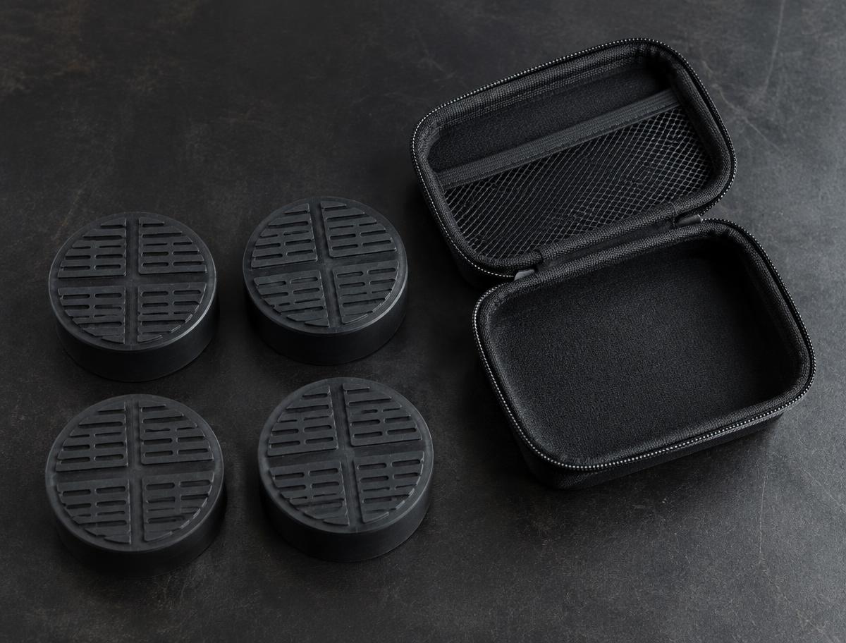 Four rubber jack pucks arranged beside an open zipped storage case on a dark bench